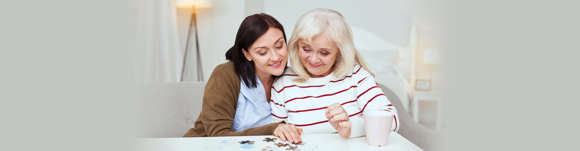 senior woman and a caregiver playing puzzle